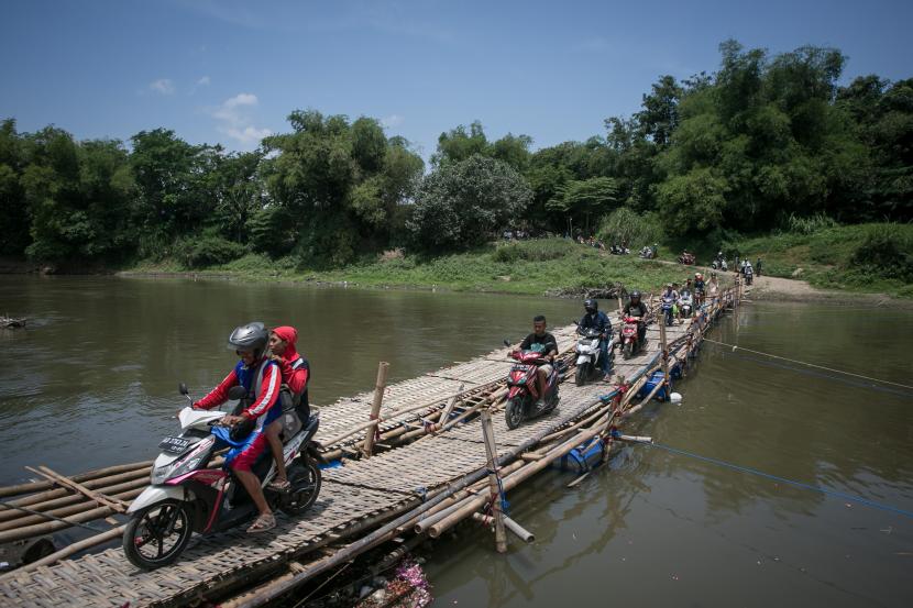 Sejumlah pengendara sepeda motor antre melintasi jembatan sesek bambu yang menghubungkan Mojolaban, Sukoharjo dengan Kampung Sewu, Solo, Jawa Tengah, Senin (26/9/2022). Sejumlah warga terpaksa memanfaatkan jembatan sesek tersebut sebagai jalan alternatif untuk menyebrangi sungai Bengawan Solo karena jembatan utama yang menghubungkan kedua wilayah itu ditutup sementara untuk proses perbaikan.