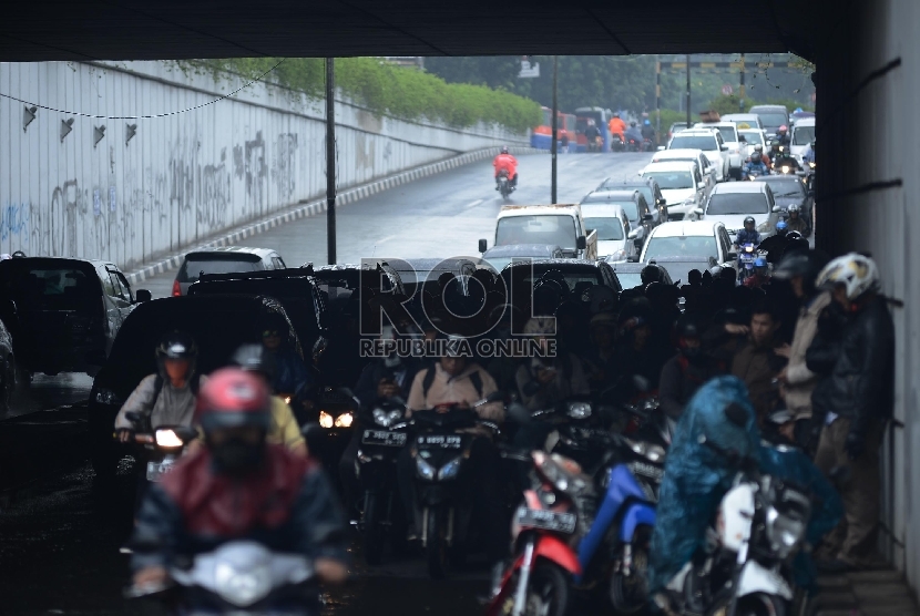 Sejumlah pengendara sepeda motor berteduh menunggu hujan reda di underpass Pasar Minggu-Kalibata, Jakarta Selatan, Senin (12/1). (Republika/Raisan Al Farisi)