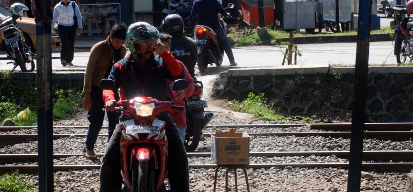 Sejumlah pengendara sepeda motor melintasi perlintasan rel kereta api tanpa palang pintu di Palmerah, Jakarta, Rabu (21/3). (Republika/Agung Fatma Putra)