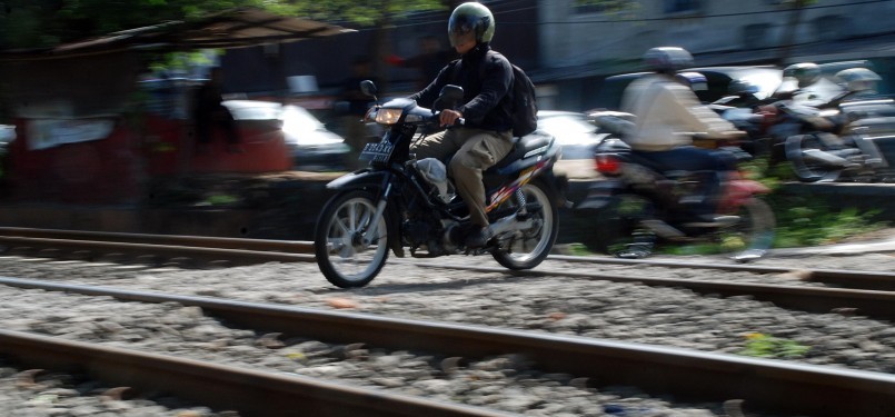 Sejumlah pengendara sepeda motor melintasi perlintasan rel kereta api tanpa palang pintu di Palmerah, Jakarta, Rabu (21/3). (Republika/Agung Fatma Putra)