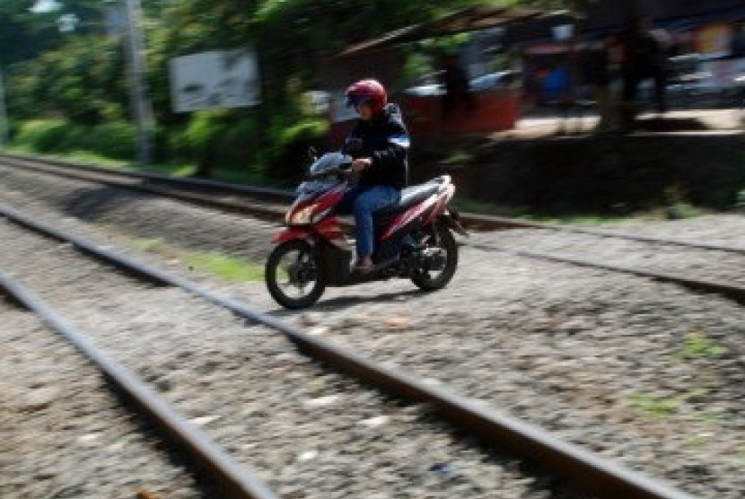 Sejumlah pengendara sepeda motor melintasi perlintasan rel kereta api tanpa palang pintu di Palmerah, Jakarta, Rabu (21/3). (Republika/Agung Fatma Putra)