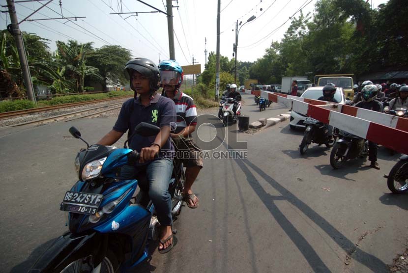 Sejumlah pengendara sepeda motor menunggu di depan pintu perlintasan kereta api kawasan Kalibata, Jakarta Selatan, Jumat (19/9).( Republika/Raisan Al Farisi)