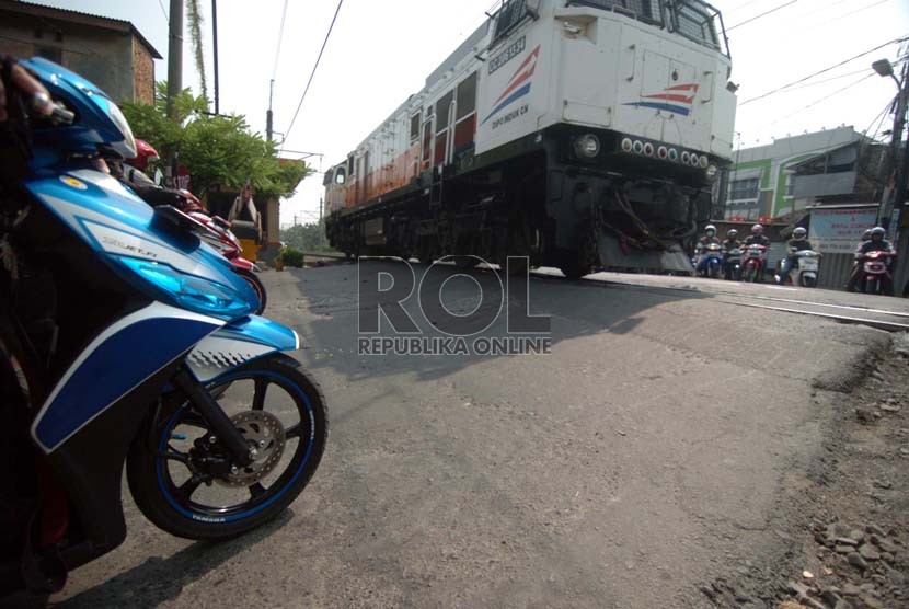 Sejumlah pengendara sepeda motor menunggu di depan pintu perlintasan kereta api kawasan Kalibata, Jakarta Selatan, Jumat (19/9).( Republika/Raisan Al Farisi)