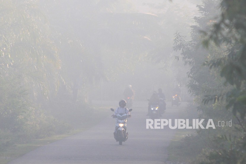 Sejumlah pengguna jalan menembus kabut asap yang menutupi kawasan jalan Desa Suak Timah, Samatiga, Aceh Barat, Aceh, Selasa (30/7/2019). 