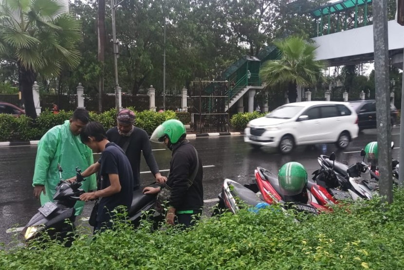 Sejumlah pengojek daring berusaha menyalakan sepeda motor yang terendam banjir di Jalan Asia Afrika, Senayan, Jakarta Pusat, Selasa (17/12).