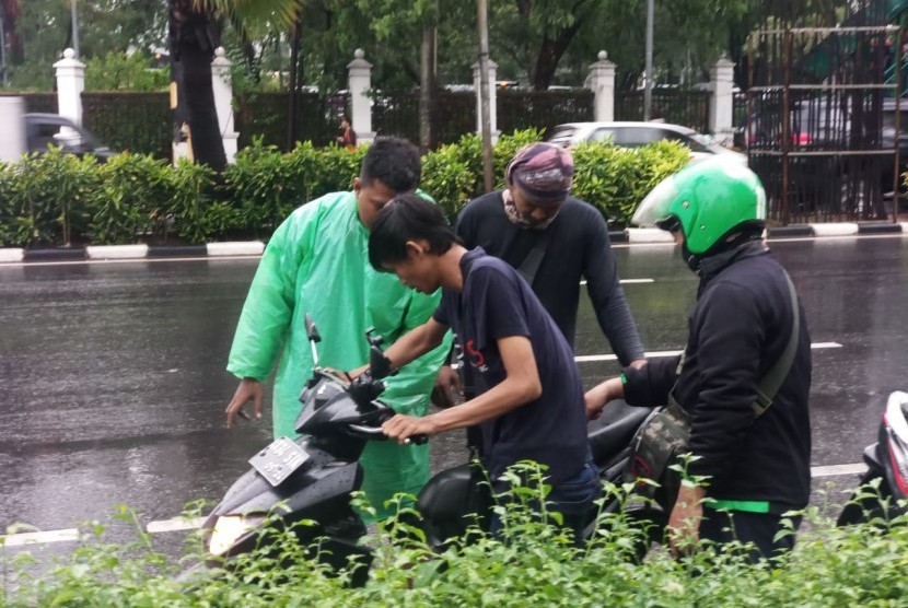 Sejumlah pengojek daring berusaha menyalakan sepeda motor yang terendam banjir di Jalan Asia Afrika, Senayan, Jakarta Pusat, Selasa (17/12).