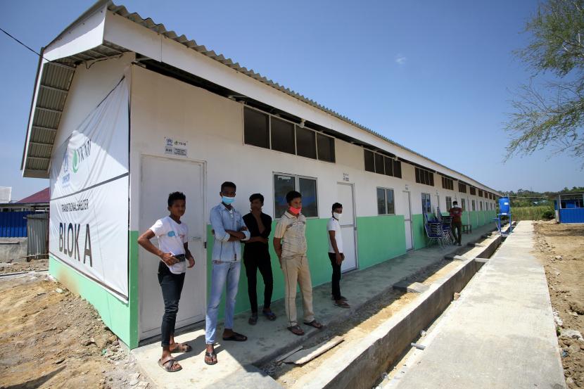 Sejumlah pengungsi etnis Rohingya berdiri di tempat perlindungan (shelter) yang baru diresmikan di Desa Meunasah Mee, Lhokseumawe, Aceh, Rabu (24/2/2021). UNHCR meresmikan sebanyak 30 unit shelter baru dengan fasilitas satu unit ruang belajar, 28 unit toilet, lima unit tempat cuci, satu unit dapur umum, lapangan bola voli dan takraw untuk ditempati 108 orang sisa pengungsi Rohingya di Aceh.