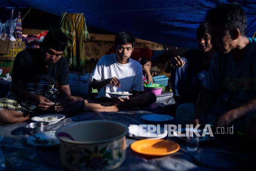 Sejumlah pengungsi korban gempa makan malam di tenda darurat yang mereka buat di kompleks Stadion Manakarra, Mamuju, Sulawesi Barat, Ahad (17/1/2021). BNPB menyatakan berdasarkan data per 17 Januari pukul 14.00 WIB jumlah korban gempa bumi Sulawesi Barat yang meninggal berjumlah 73 orang dan sebanyak 27.850 orang mengungsi di 25 titik pengungsian. 
