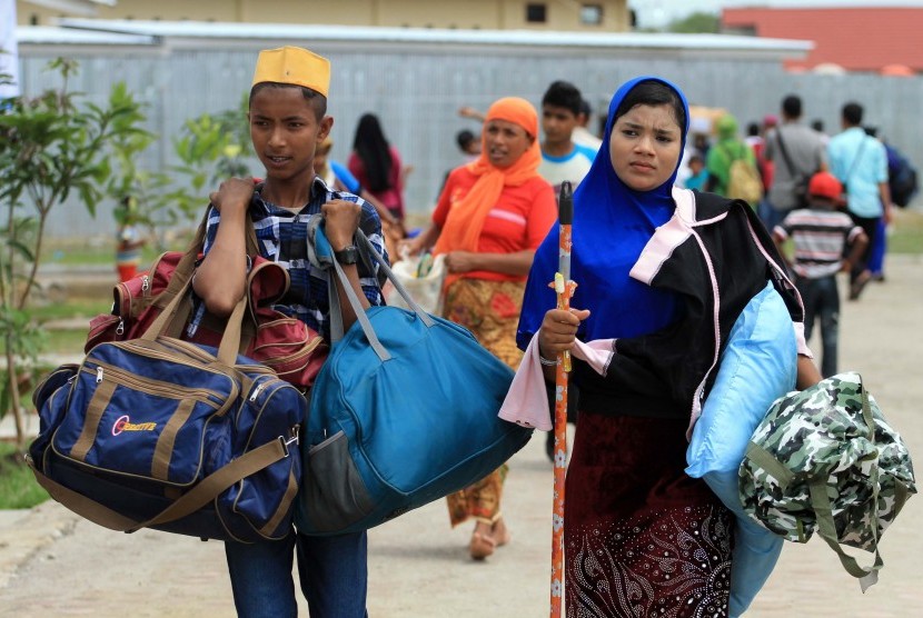 Sejumlah pengungsi muslim etnis Rohingya mengangkut barang milik mereka dari BLK penampungan sementara menuju rumah barak di Desa Blang Ado, Kuta Makmur, Aceh Utara, Provinsi Aceh. Kamis (6/8).