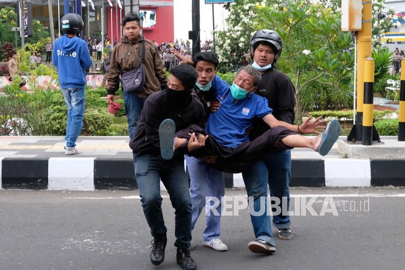 Sejumlah pengunjuk rasa menolong seorang warga yang terkena gas air mata saat demonstrasi menentang Omnibus Law Undang-Undang (UU) Cipta Kerja di Kota Magelang, Jawa Tengah, Jumat (9/10/2020). Unjuk rasa tersebut berakhir ricuh dan mengakibatkan sejumlah fasilitas umum rusak. PWI menyayangkan aparat yang dalam demo bersikap represif ke jurnalis.