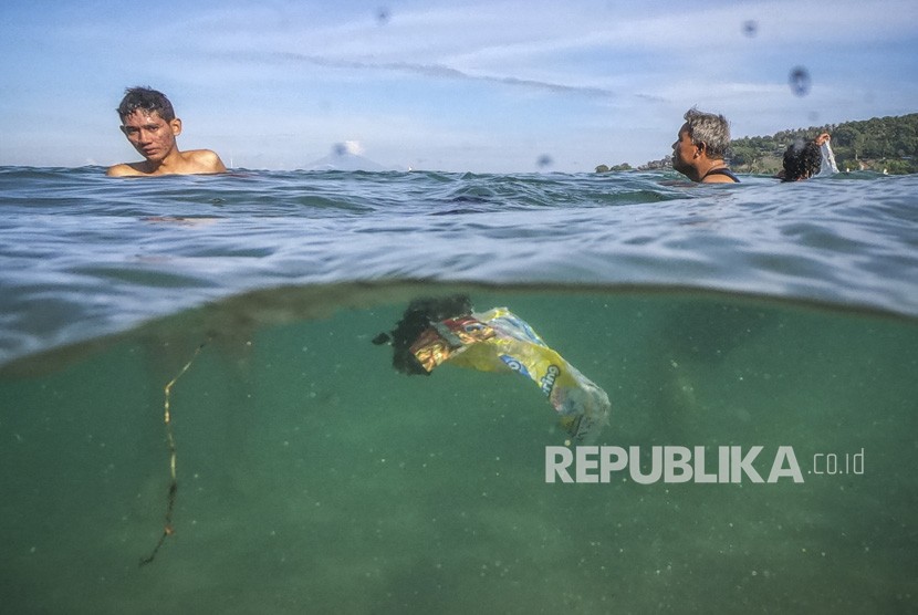 Sejumlah pengunjung berenang di dekat sampah plastik yang hanyut terbawa arus di pantai wisata Senggigi, Lombok Barat, NTB. 