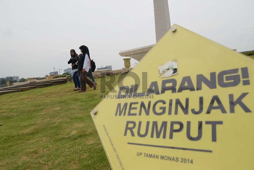 Sejumlah pengunjung berjalan di rumput dengan mengabaikan papan aturan yang terpasang di Monumen Nasional (Monas) Jakarta Pusat, Kamis, (4/12).