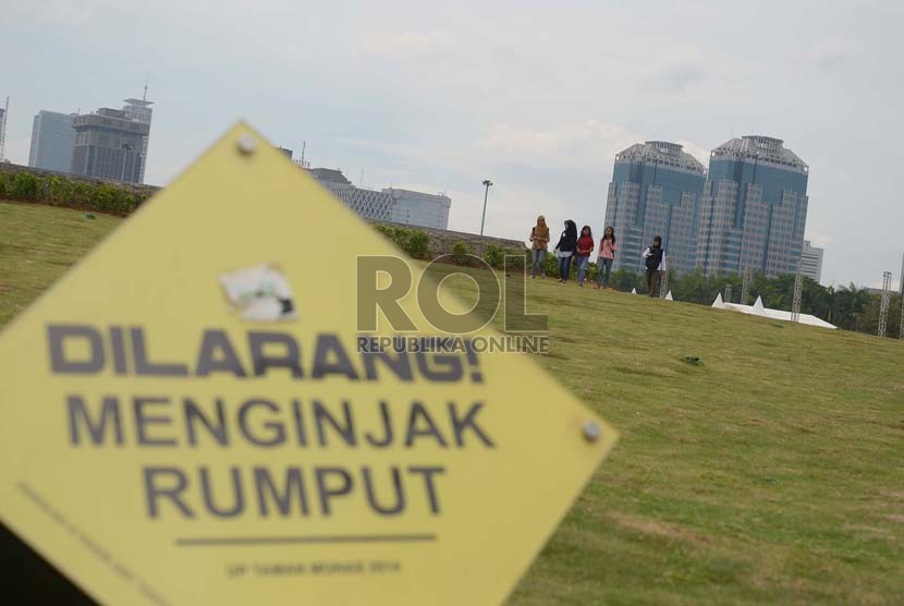 Sejumlah pengunjung berjalan di rumput dengan mengabaikan papan aturan yang terpasang di Monumen Nasional (Monas) Jakarta Pusat, Kamis, (4/12).