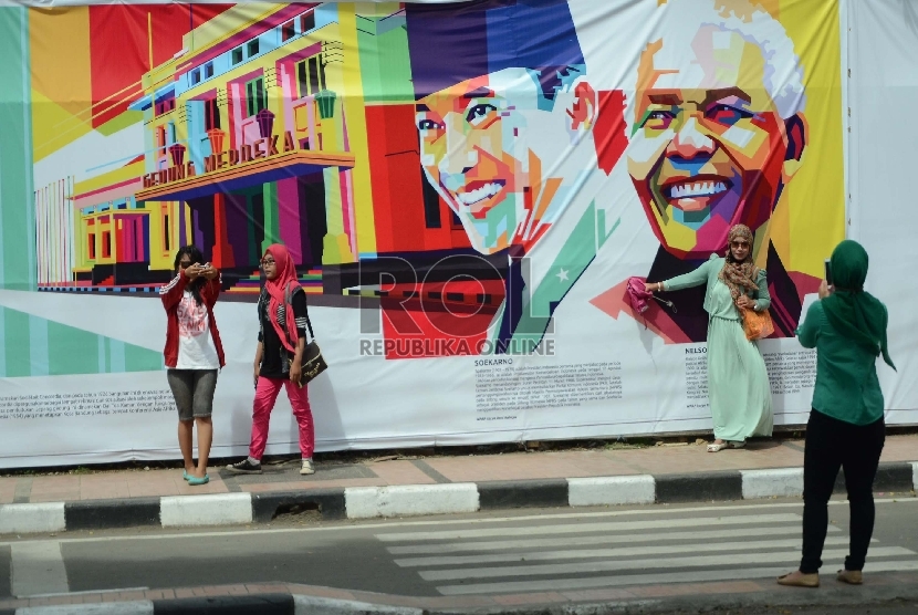 Sejumlah pengunjung berselfie ria di gambar Soekarno dan Nelson Mandela. Meski puncak perayaan Konferensi Asia Afrika (KAA) ke-60 telah usai namun kepadatan pengunjung masih terjadi di kawasan Gedung Merdeka, Jl Asia Afrika, Kota Bandung, Ahad (26/4). 