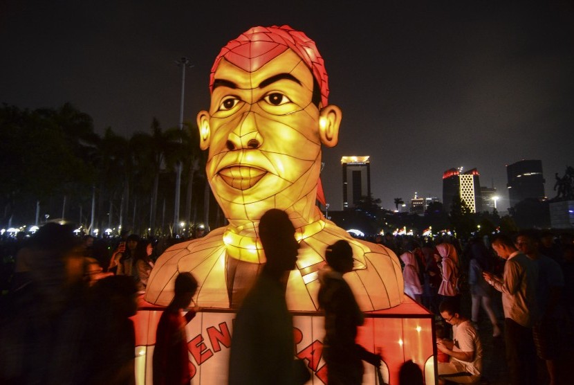 Sejumlah pengunjung melintas di dekat lampion karakter pahlawan nasional Jenderal Besar Sudirman pada acara Festival of Light di Monas, Jakarta Pusat, Sabtu (17/8). Festival lampion dan laser bertemakan HUT ke-74 Kemerdekaan RI itu berlangsung dari 14-25 Agustus 2019.