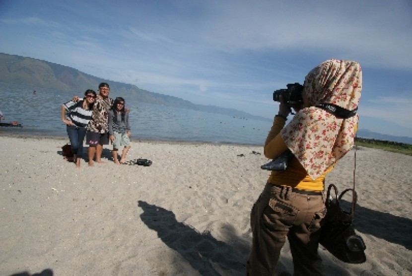Sejumlah pengunjung menikmati objek wisata Pasir Putih Parbaba di kawasan perairan Danau Toba, Kec. Pangururan, Kab.Samosir, Sumut. Pemkab Samosir meraih PAD sebesar Rp 242.815.000 selama libur Lebaran 2022.
