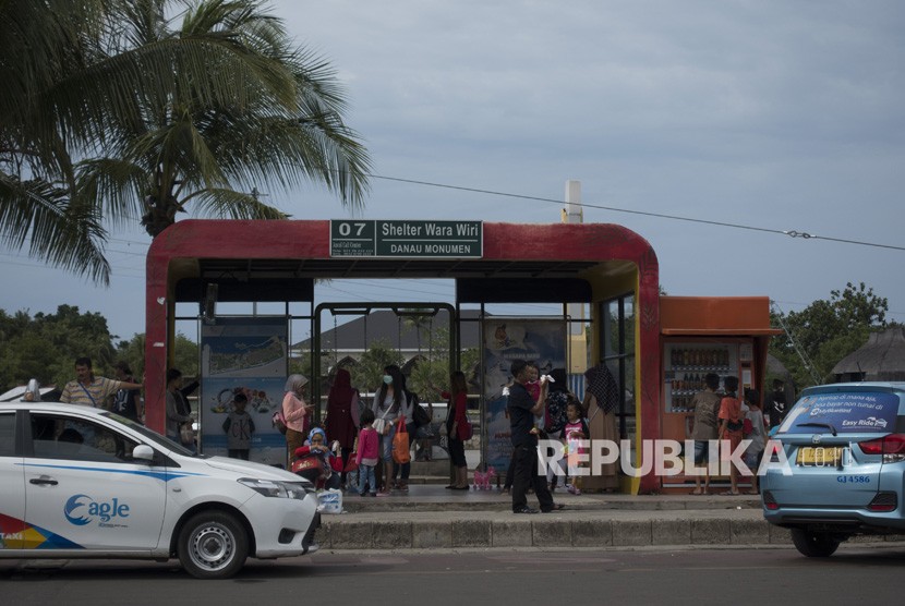 Sejumlah pengunjung menunggu di halte bus wara wiri di dalam kawasan Ancol, Jakarta, Jumat (29/12). 