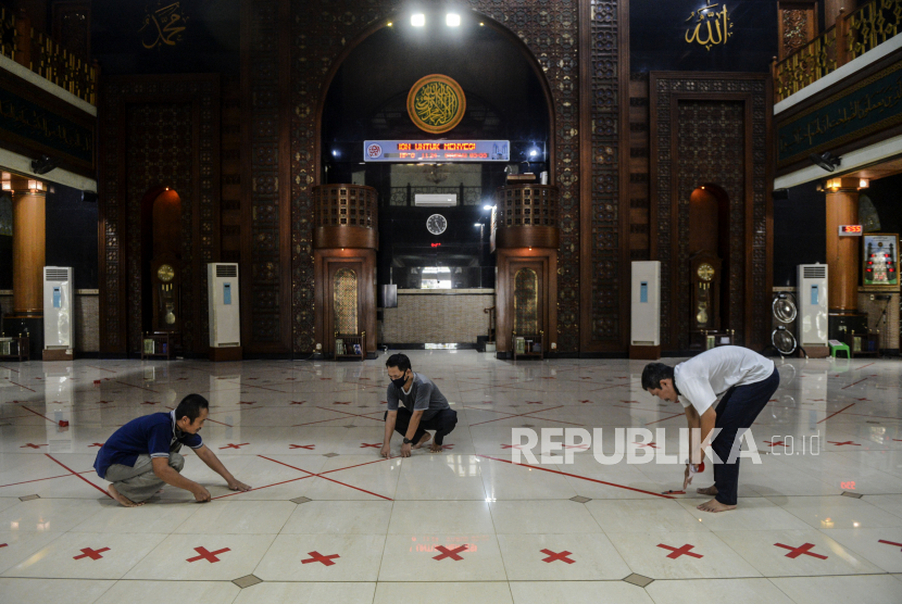 Sejumlah pengurus masjid memasangkan tanda silang untuk membatasi shaf jamaah di Masjid Agung Al-Barkah, Kota Bekasi, Jawa Barat.