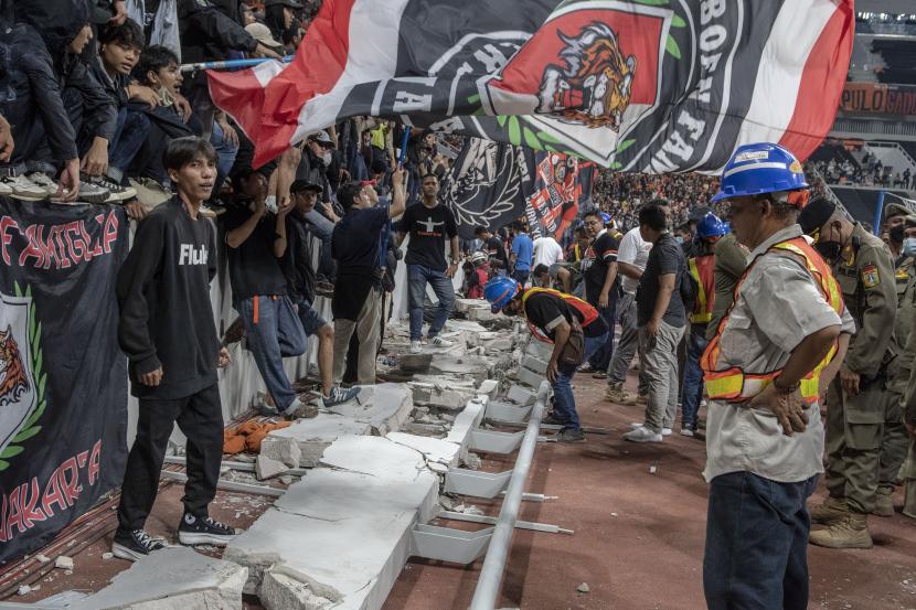 Sejumlah penonton berdiri di atas puing pagar pembatas yang roboh saat peresmian Stadion Jakarta International Stadium (JIS), Jakarta Utara, Ahad ( 24/7/2022) malam WIB. 