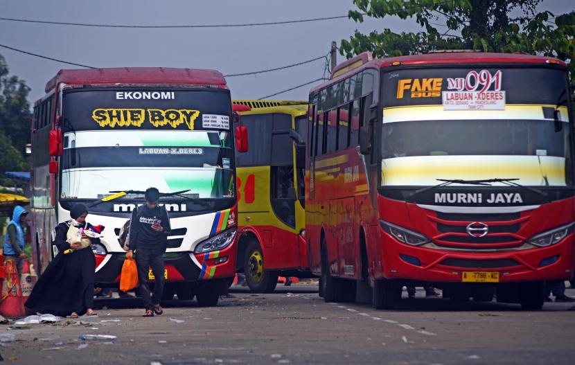 Sejumlah penumpang berjalan di depan bus di terminal Pakupatan, Serang, Banten, Selasa (12/7/2022).