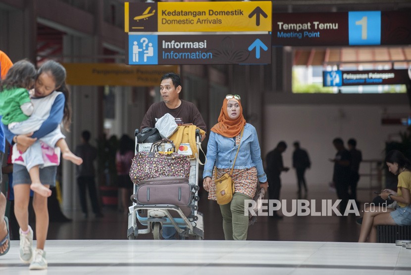 Sejumlah penumpang membawa barang bawaan di Terminal Domestik Bandara Ngurah Rai, Senin (18/12).