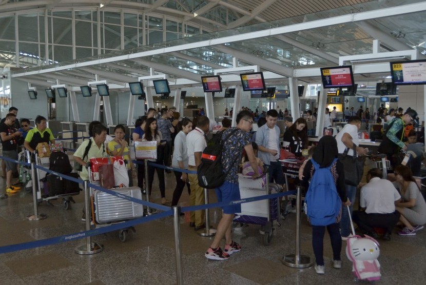 Sejumlah penumpang mengantre di terminal keberangkatan Bandara Ngurah Rai, Bali, Senin (7/3). 