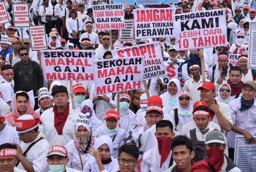Sejumlah perawat yang tergabung dalam Persatuan Perawat Nasional Indonesia (PPNI) membawa poster saat menggelar unjuk rasa di depan Gedung DPR/MPR, Jakarta, Kamis (16/3). 