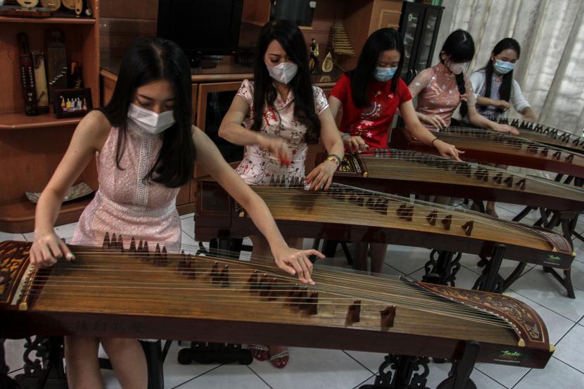 Sejumlah perempuan menggunakan masker saat berlatih memainkan alat musik tradisional Kecapi China (Guzheng) di Medan, Sumatera Utara, Jumat (5/2/2021). Kegiatan tersebut dilakukan jelang pementasan musik pada Tahun Baru Imlek 2572 di Medan.
