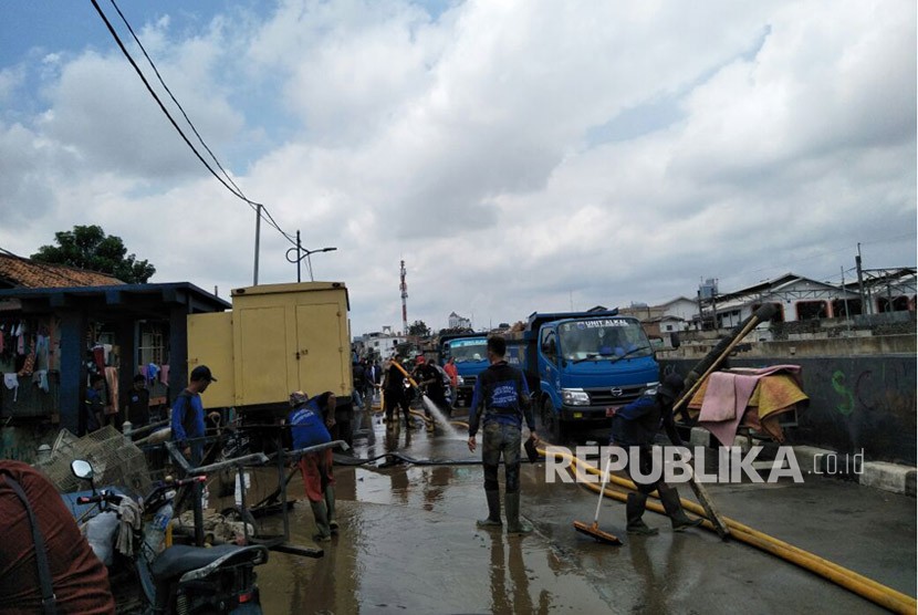 Sejumlah personel dari Suku Dinas Sumber Daya Air Jakarta Timur membersihkan sisa lumpur akibat luapan Sungai Ciliwung, kawasan Kampung Melayu, Jumat (9/2).