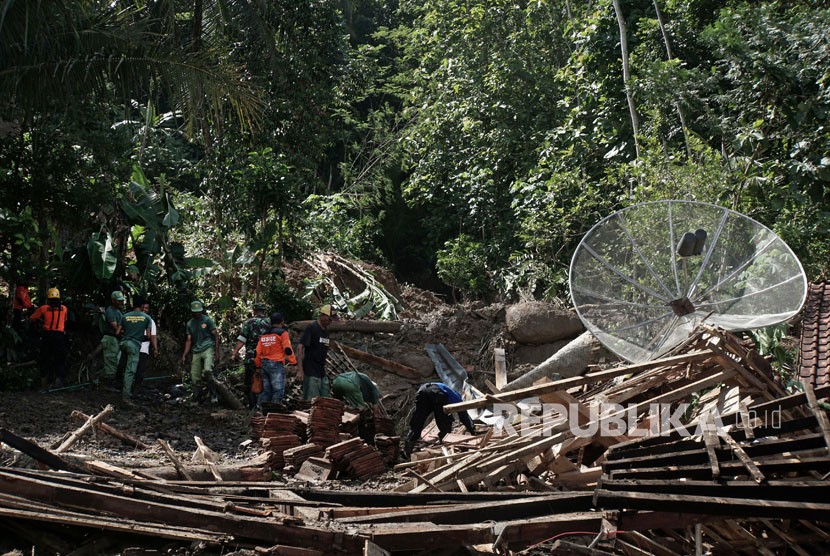 Sejumlah personel Tagana bersama relawan dan warga membersihkan puing rumah, yang roboh terkena longsor di Desa Cihonje, Gumelar, Banyumas, Jawa Tengah, Senin (18/12). 