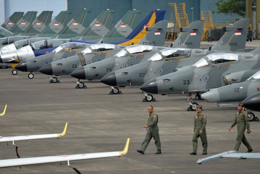 Sejumlah personel TNI AU berjalan di dekat deretan pesawat jet tempur yang terparkir. Ilustrasi