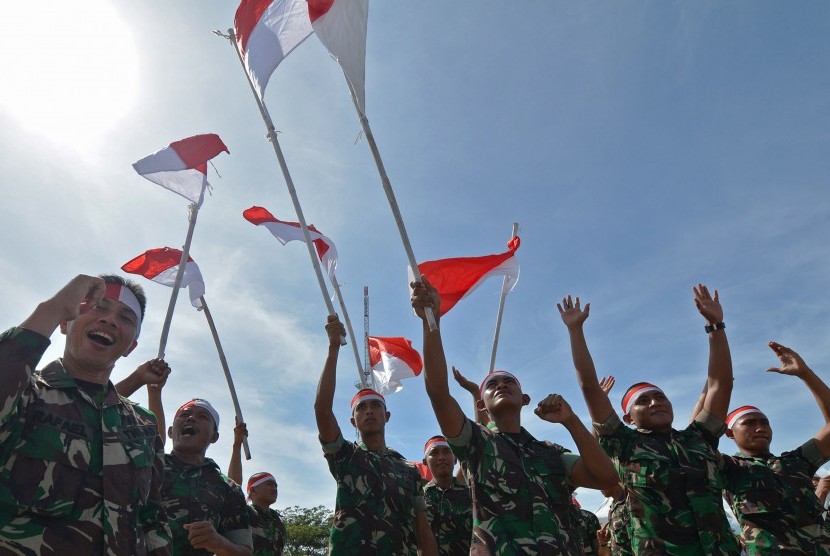 Sejumlah personel TNI melambaikan bendera merah putih.