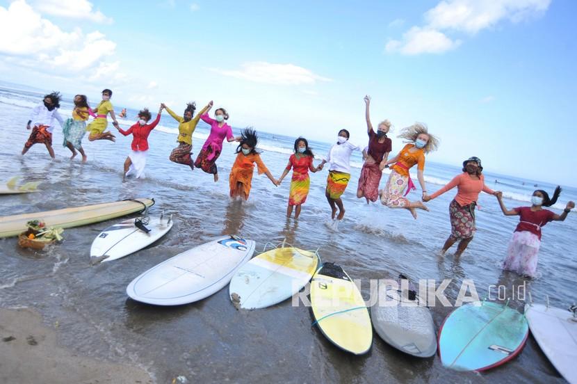 Sejumlah peselancar wanita yang mengenakan busana kebaya berfoto sebelum berselancar di Pantai Kuta, Badung, Bali, Jumat (16/4/2021). Kegiatan yang diikuti puluhan perempuan termasuk sejumlah WNA tersebut dilakukan untuk menyambut peringatan Hari Kartini serta membangkitkan sektor pariwisata Bali yang terdampak pandemi COVID-19. 