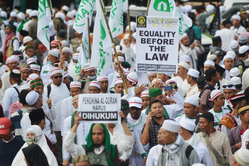 Sejumlah peserta aksi membawa poster saat long march menuju Monas untuk mengikuti aksi 212 atau 2 Desember di Jalan MH Thamrin, Jakarta, Jumat (2/12). 