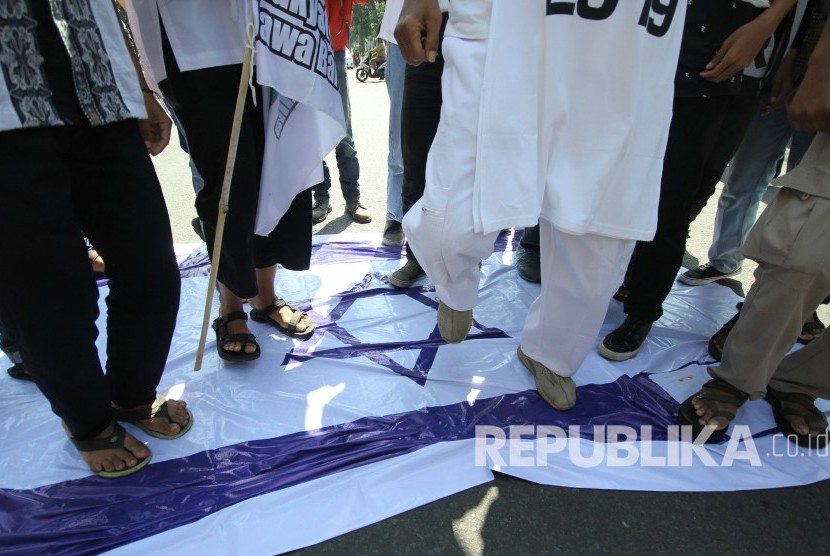 Sejumlah peserta aksi menginjak-nginjak bendera Zionis Israel (ilustrasi).