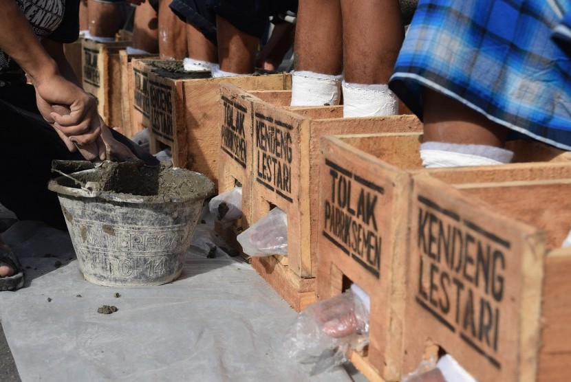 Sejumlah petani Pegunung Kendeng bersiap-siap untuk memasung kakinya dengan semen saat menggelar aksi di depan Istana Merdeka, Jakarta, Rabu (15/3).