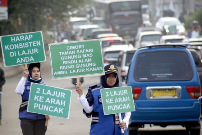 Sejumlah petugas Badan Pengelola Transportasi Jabodetabek (BPTJ) membentangkan papan informasi sosialisasi sistem kanalisasi di Jalur Puncak, Bogor, Jawa Barat, Ahad (27/10/2019). Sosialisasai tersebut untuk menginformasikan penerapan rekayasa lalu lintas kanalisasi 2:1, sebagai pengganti sistem satu arah (one way). 