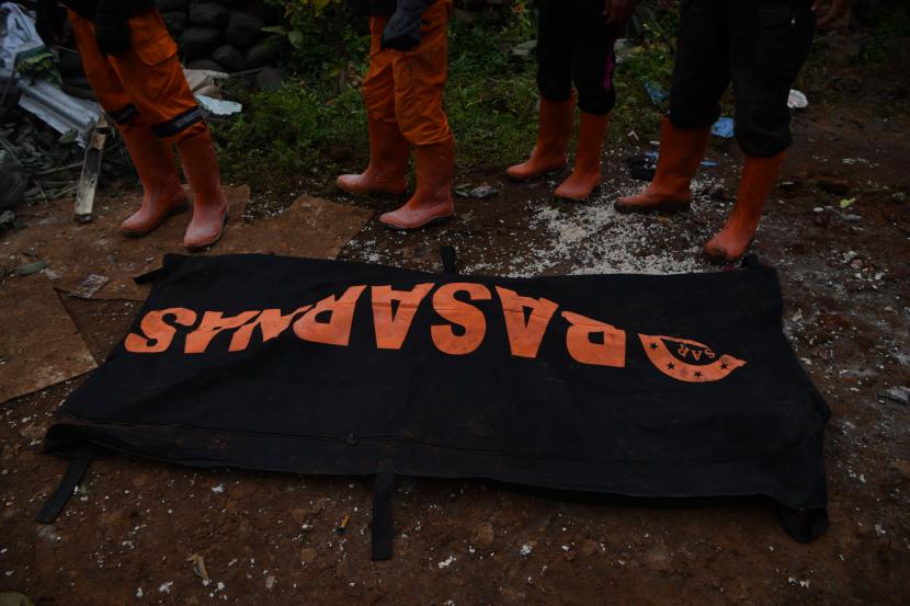 Sejumlah petugas berdiri di samping kantong jenazah yang berisi korban tanah longsor yang berhasil dievakuasi di Ngetos, Nganjuk, Jawa Timur, Senin (15/2/2021). Pencarian hari pertama korban tanah longsor, tim SAR berhasil mengevakuasi sedikitnya tujuh jenazah korban.