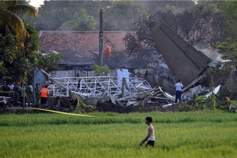 Sejumlah petugas dan warga menyaksikan bangkai pesawat Fokker 27 yang jatuh di komplek perumahan Rajawali kawasan Lapangan Udara Halim Perdana Kusuma, Jakarta, Kamis (21/6). 