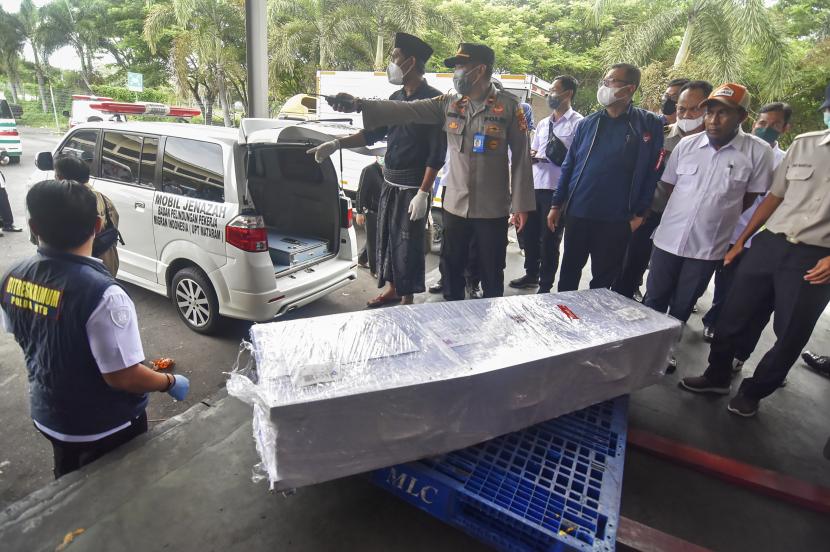 Sejumlah petugas dari kepolisian dan Kementerian Ketenagakerjaan bersiap mengangkat peti jenazah TKI ilegal korban meninggal dunia dalam kecelakaan kapal di perairan Malaysia ke dalam mobil ambulans di Terminal Kargo Bandara Internasional Lombok (BIL), Praya, Lombok Tengah, NTB, Rabu (5/1/2022). Sebanyak tujuh jenazah TKI asal NTB yang meninggal dunia dalam kecelakaan kapal di perairan Malaysia telah tiba di Lombok.