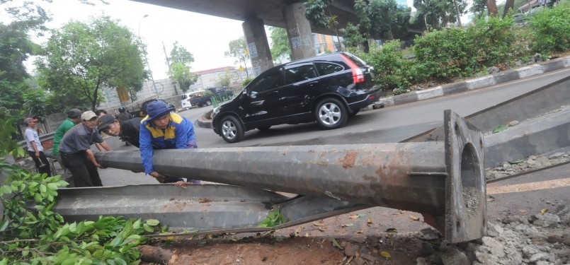 Sejumlah petugas dibantu warga mengevakuasi tiang lampu penerangan jalan yang tumbang akibat angin ribut di kawasan Mampang Prapatan, Jakarta Selatan, Rabu (26/10). (Republika/Aditya Pradana Putra)