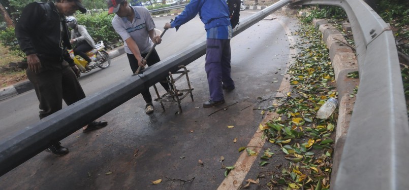 Sejumlah petugas dibantu warga mengevakuasi tiang lampu penerangan jalan yang tumbang akibat angin ribut di kawasan Mampang Prapatan, Jakarta Selatan, Rabu (26/10). (Republika/Aditya Pradana Putra)