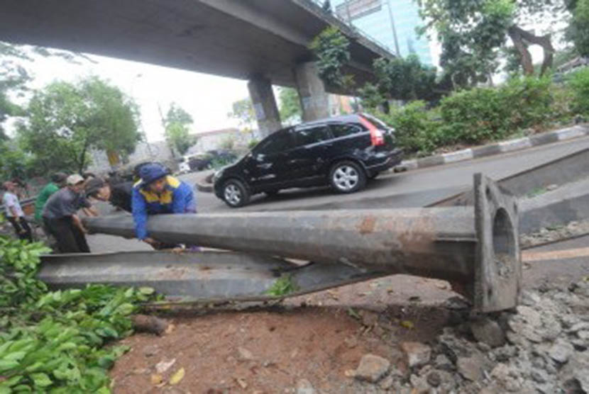 Sejumlah petugas dibantu warga mengevakuasi tiang lampu penerangan jalan yang tumbang akibat angin ribut di kawasan Mampang Prapatan, Jakarta Selatan, Rabu (26/10). (Republika/Aditya Pradana Putra)