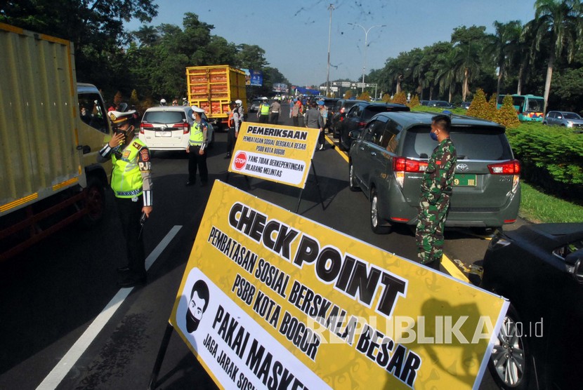 Sejumlah petugas gabungan melakukan pemeriksaan saat pelaksanaan Pembatasan Sosial Berskala Besar (PSBB) di pintu keluar Tol Jagorawi, Kota Bogor, Jawa Barat, Rabu (15/4).