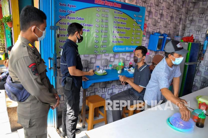 Sejumlah petugas gabungan dari Kepolisian dan Satpol PP melakukan razia pengunjung warung makan yang melanggar aturan PPKM (Pemberlakuan Pembatasan Kegiatan Masyarakat) darurat di Bekasi, Jawa Barat, Kamis (8/7/2021). Pada sidak tersebut pengusaha dan pengunjung yang melanggar peraturan selama PPKM darurat dari tanggal 3-20 Juli 2021 diberikan sanksi denda guna memberikan efek jera kepada pelanggar protokol kesehatan. 