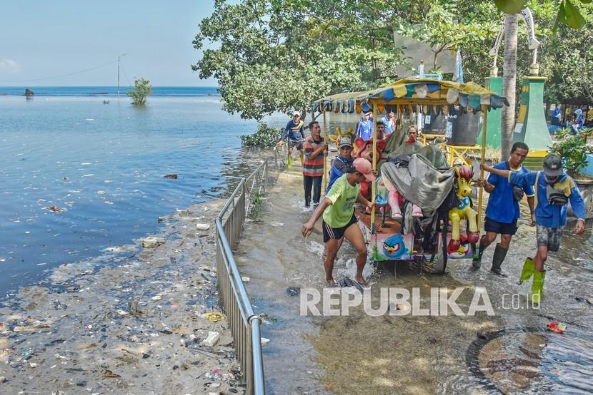 Pemkot Mataram Imbau Warga Rayakan Tahun Baru di Rumah. Sejumlah petugas kebersihan menarik odong-odong saat rob di Taman Wisata Loang Baloq, Mataram, NTB, Kamis (27/5/2021). Gelombang pasang menyebabkan air laut naik dan merendam kawasan taman wisata tersebut sejak Rabu (26/5).