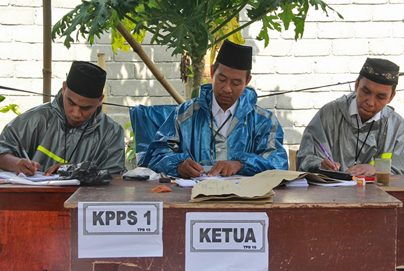 Sejumlah petugas Kelompok Panitia Pemungutan Suara (KPPS) mengenakan jas hujan saat pemungutan suara Pilkada serentak 2015 Walikota dan Wakil Walikota Mataram di Tempat Pemungutan Suara (TPS) 10, Lingkungan Kebon Jaya Timur, Kelurahan Monjok, Kecamatan Sel