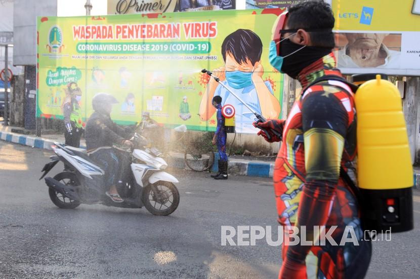 Sejumlah petugas kepolisian berpakaian superhero menyemprotkan cairan disinfektan di jalan Panglima Sudirman kawasan Kebonagung, Pasuruan, Jawa Timur, Kamis (9/4/2020). Penyemprotan cairan disinfektan tersebut bertujuan untuk mengantisipasi penyebaran Virus Corona (COVID-19).