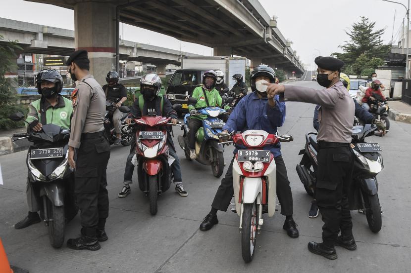 Sejumlah petugas Kepolisian (kiri) mengarahkan pengendara motor untuk berputar arah di PPKM darurat di Kalimalang, Jakarta Timur, Rabu (7/7/2021). Pada hari ke-5 PPKM darurat di wilayah perbatasan Bekasi dan Jakarta arus lalu lintas terpantau lancar. 