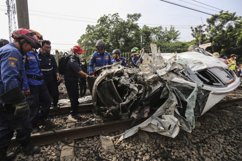 Sejumlah petugas melakukan evakuasi mobil yang tertabrak KRL di kawasan Rawageni, Kecamatan Cipayung, Kota Depok, Jawa Barat, Rabu (20/4/2022). 